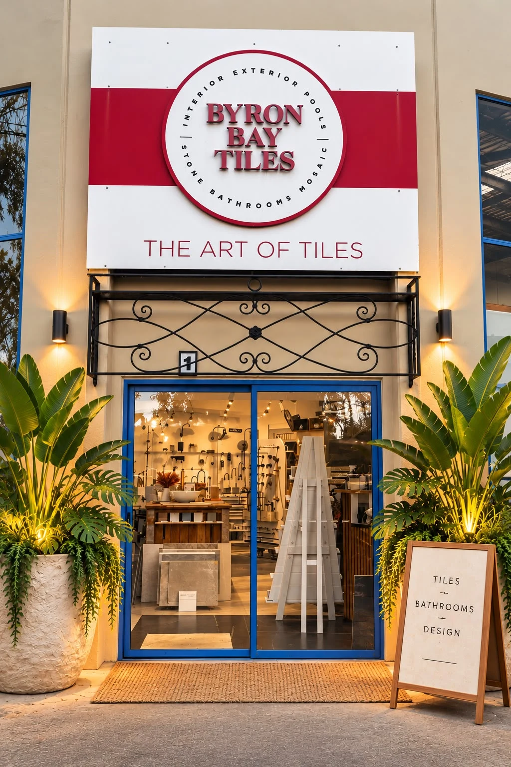 The Byron Bay Tiles entrance, with its red and white sign and illuminated plant displays